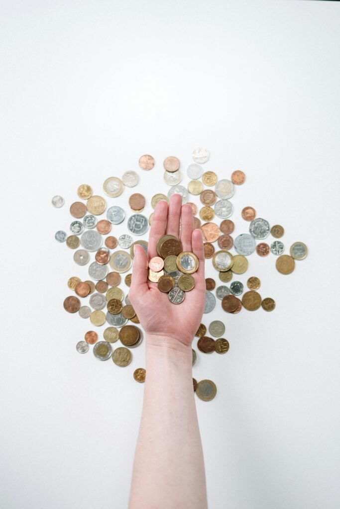 An open hand holds various coins on a white surface, symbolizing finance and currency exchange.
