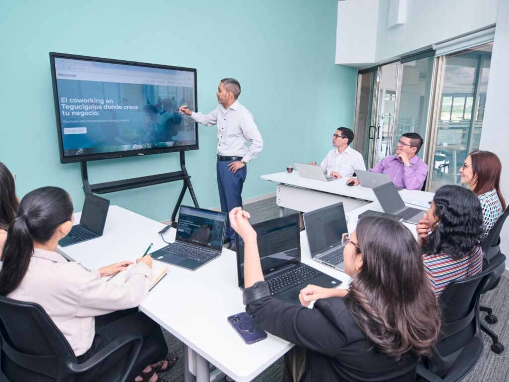 Professional team engaged in a business presentation with laptops and a projector screen.