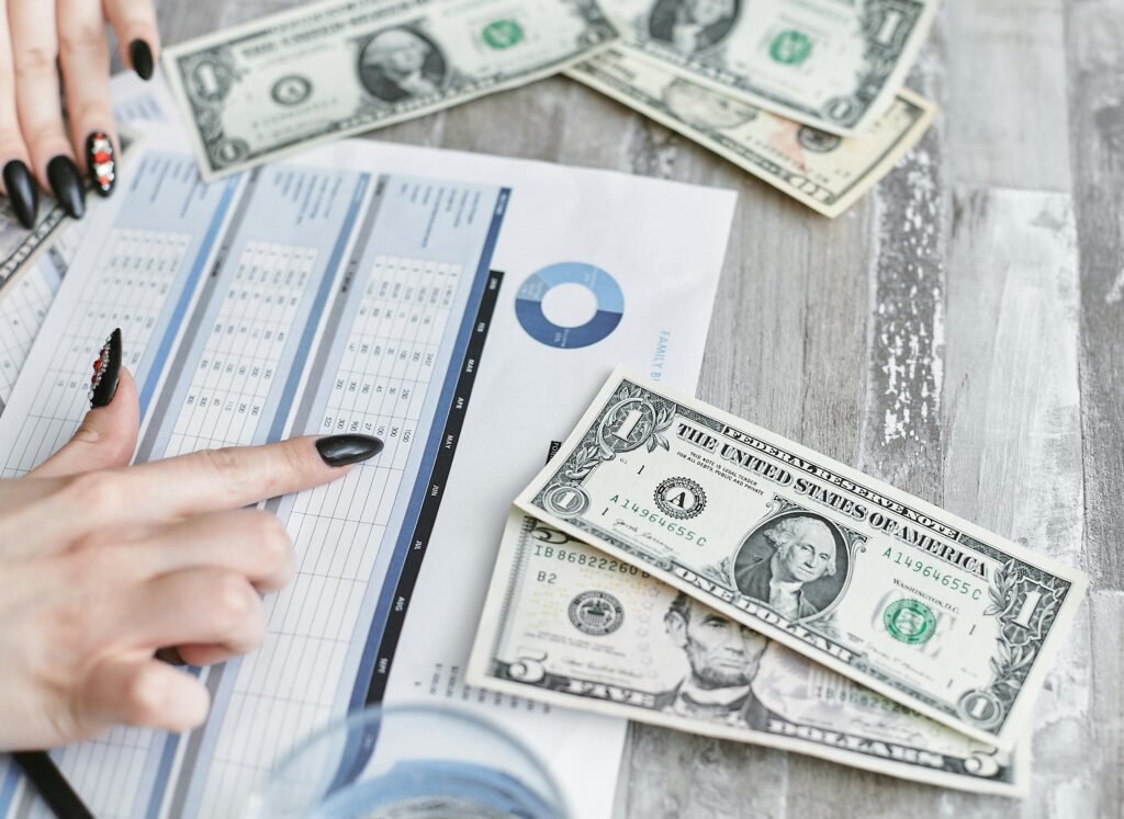 Close-up of hands analyzing financial document with US dollar bills on table.