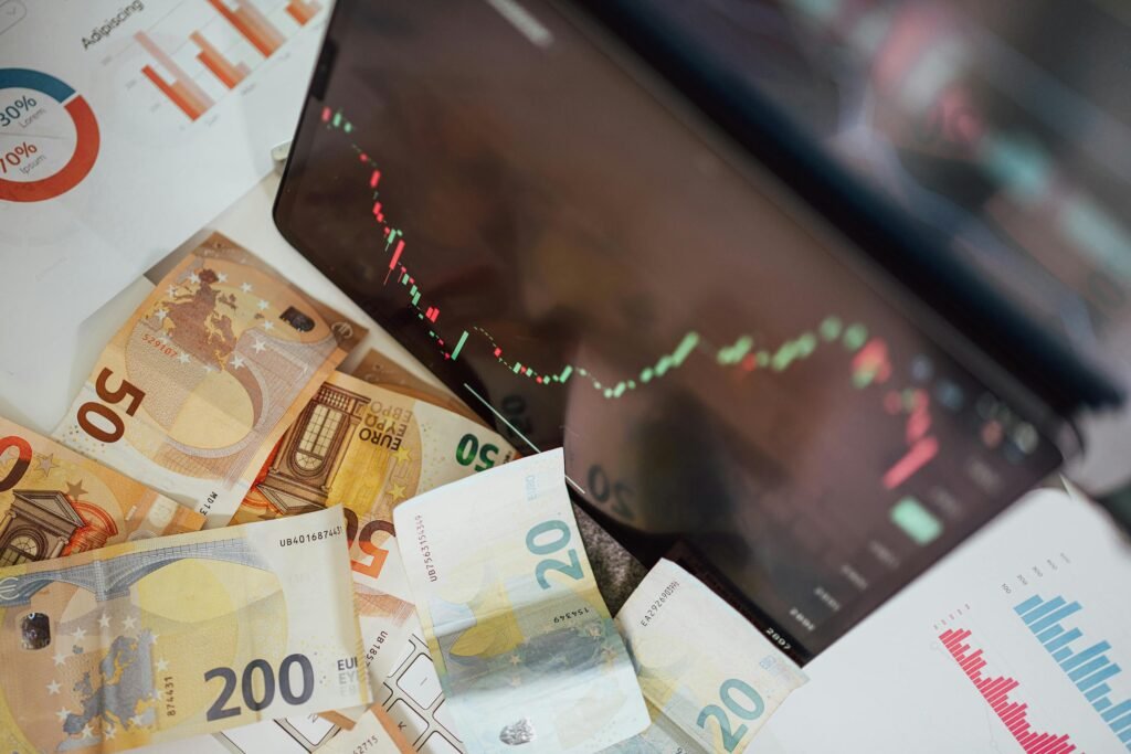 Close-up of euro banknotes with a digital stock market chart displaying a downward trend, symbolizing financial volatility.